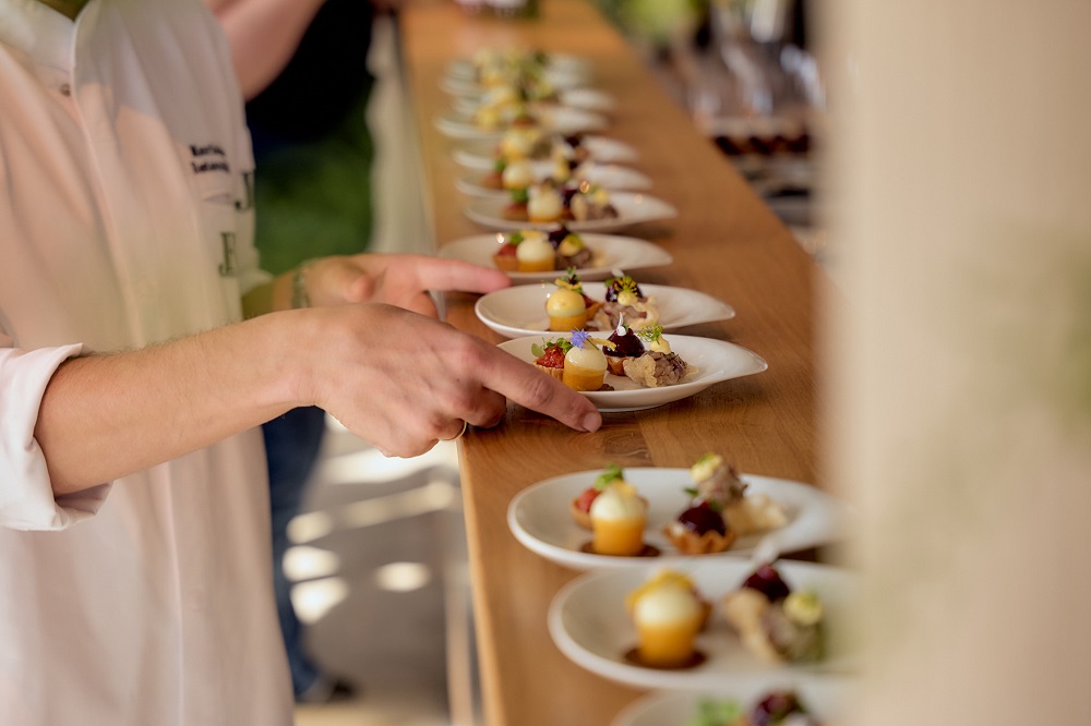 Koch richtet eine Reihe kunstvoller Häppchen auf Tellern beim Event „Hamburgs Sterne“ by OPEN MOUTH Hamburg Food Festival an.